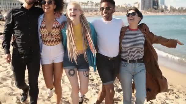 Gelukkig gevarieerde vrienden wandelen op het strand in omhelzing — Stockvideo