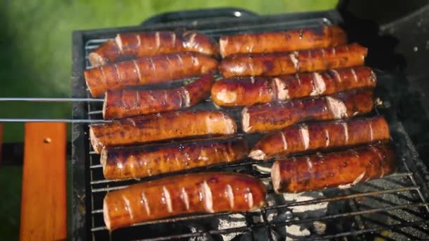 Asar sabrosas salchichas en la parrilla de barbacoa — Vídeo de stock