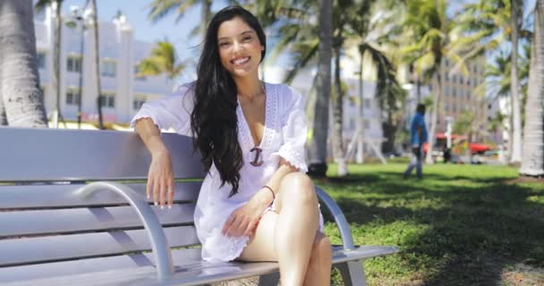 Hermosa chica en vestido blanco en el banco en el parque — Vídeos de Stock