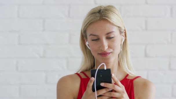 Симпатичная женщина слушает музыку и пользуется смартфоном — стоковое видео