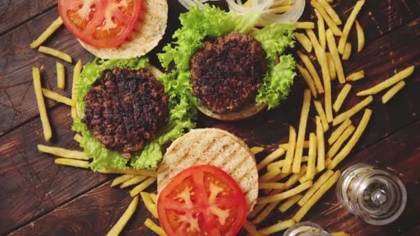 Dos sabrosas hamburguesas a la parrilla hechas en casa con carne de res, tomate, cebolla y lechuga — Vídeo de stock