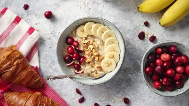 Ciotola in ceramica di farina d'avena porridge con banana, mirtilli rossi freschi e noci — Video Stock