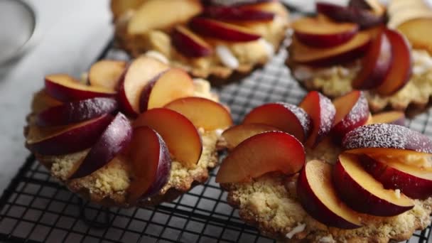 Homemade crumble tarts with fresh plum slices placed on iron baking grill — Stock Video