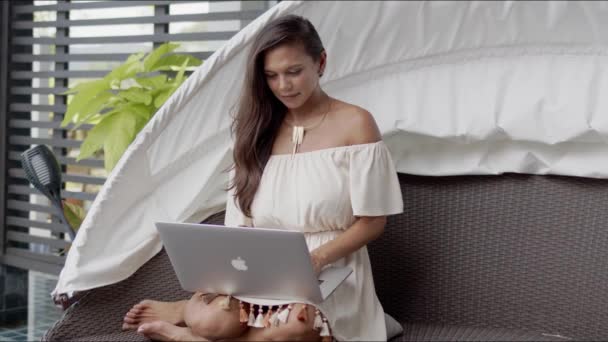 Senhora descalça feliz em roupas casuais sentado no sofá e interagindo com laptop — Vídeo de Stock