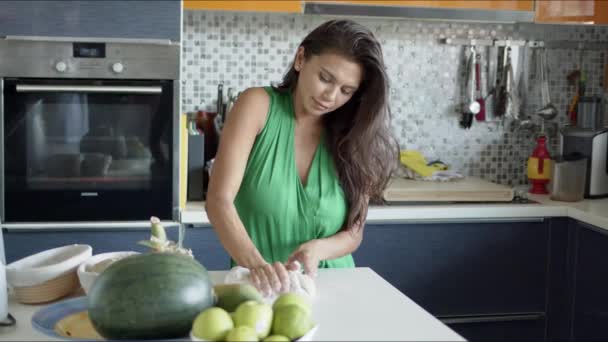 Сосредоточенные женские катящиеся тесто, стоя в одиночестве на современной светлой кухне — стоковое видео