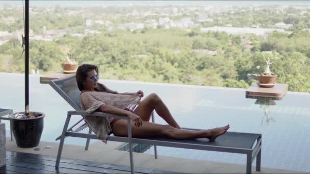 Femme couchée sur un transat sur la terrasse de la piscine de l'hôtel — Video