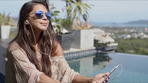 Mujer escuchando música junto a la piscina y disfrutando de un día soleado — Vídeos de Stock