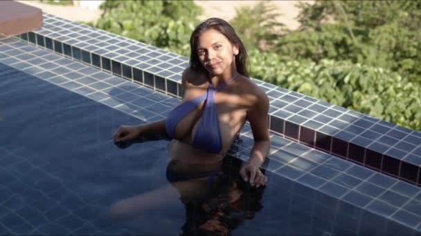 Подходит молодая женщина, отдыхающая в бассейне в солнечный день — стоковое видео