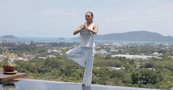 Volwassen vrouw die yoga beoefent in het zwembad tegen verbazingwekkend landschap — Stockfoto