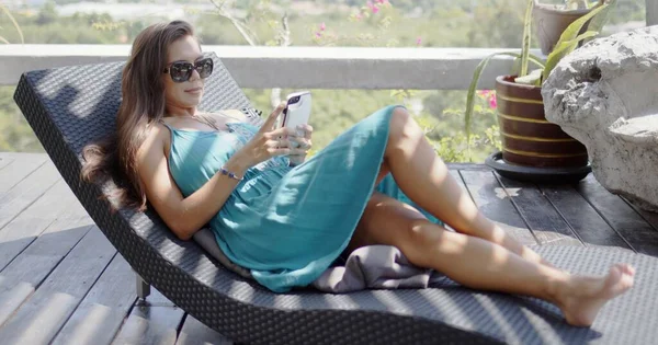 Mulher atraente com smartphone descansando no salão de chaise — Fotografia de Stock