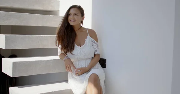 Szczęśliwa młoda kobieta siedząca na schodach i odwracająca wzrok — Zdjęcie stockowe