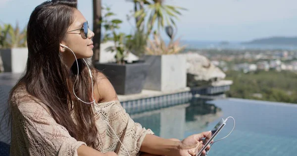 Vrouw luisteren naar muziek aan het zwembad en genieten van zonnige dag — Stockfoto