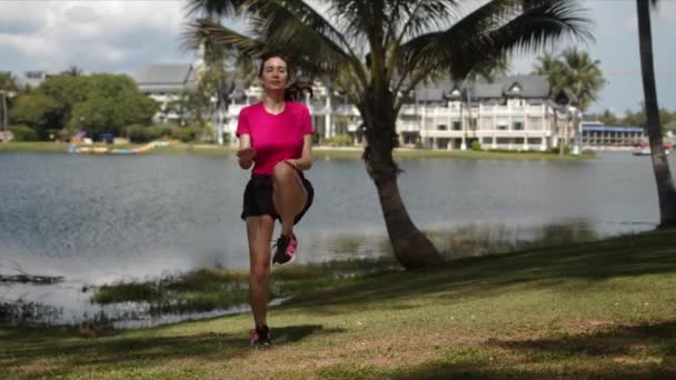 Активная женщина делает упражнения на берегу озера — стоковое видео