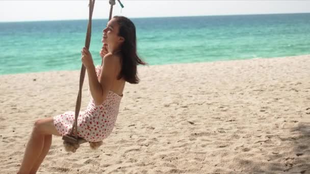 Gelukkig vrouw genieten swing op strand — Stockvideo