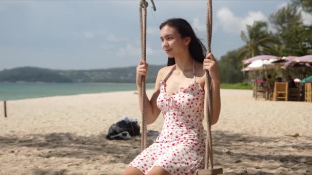 Joven mujer relajada sentada en columpio en la playa — Vídeos de Stock