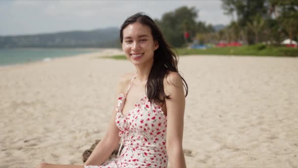 Glückliche Brünette sitzt am tropischen Strand — Stockvideo