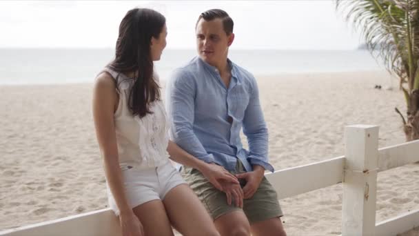 Hombre y mujer vacacionistas relajándose juntos en la costa — Vídeos de Stock