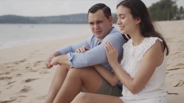 Ζευγάρι σε διακοπές κάθεται στην άμμο της παραλίας και χαμογελώντας — Αρχείο Βίντεο