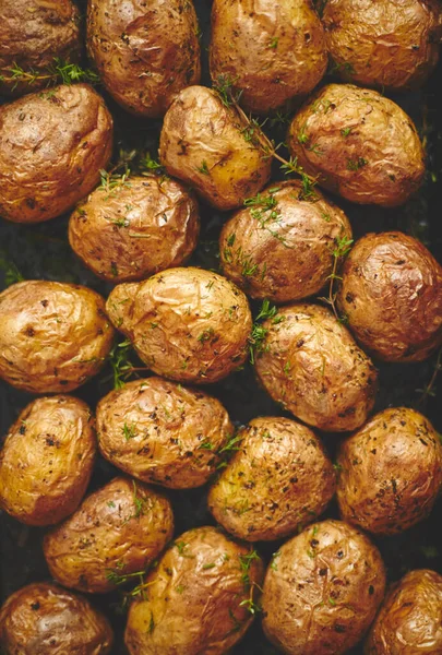 Pommes de terre entières cuites au four avec assaisonnement et herbes dans un plateau métallique. Pommes de terre rôties en vestes . — Photo