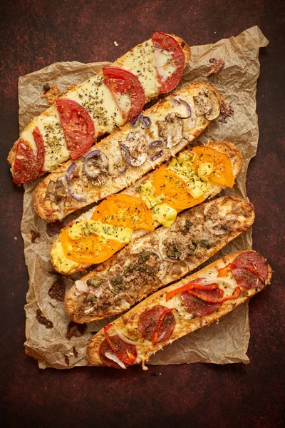Sortimento de várias coberturas sanduíches assadas. Com queijo derretido, legumes, atum, especiarias de azeitonas — Fotografia de Stock