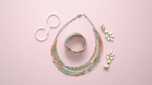 Accesorios de moda mujer. Joyas. Pendientes y collar en un elegante fondo rosa pastel. Puesta plana — Vídeos de Stock