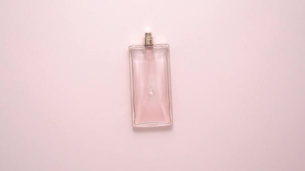 Вид зверху на розкішну пляшку парфумів на пастельній рожевій поверхні. Мінімальна композиція. Плоский прошарок — стокове відео
