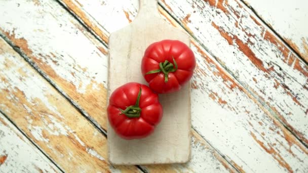Deux éco tomates fraîches placées sur une planche à découper en bois blanc. Concept d'alimentation saine — Video