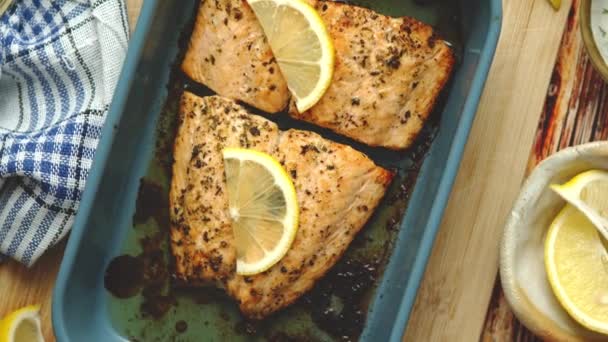 Tembakan dekat salmon panggang yang sehat disajikan dalam bukti panas keramik hidangan. Ditempatkan di papan kayu — Stok Video