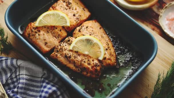 Salmón asado en plato a prueba de calor. Con eneldo aromático, limón, sal y pimienta en los lados . — Vídeo de stock