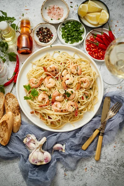 Spaghetti aux crevettes sur plaque de céramique blanche et servi avec un verre de vin blanc — Photo