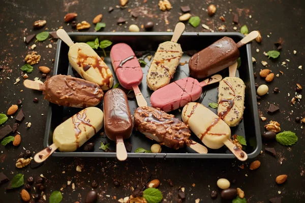 Set med läcker vit och mjölkchoklad och jordgubbsglass på en pinne serveras i metallbricka — Stockfoto