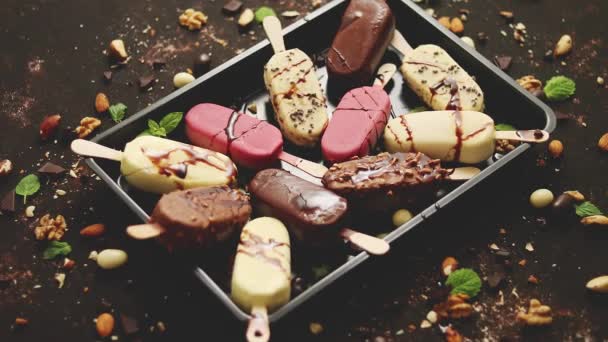 Assortiment van diverse ijslolly 's, witte en pure chocolade, met amandelen, roestige achtergrond — Stockvideo