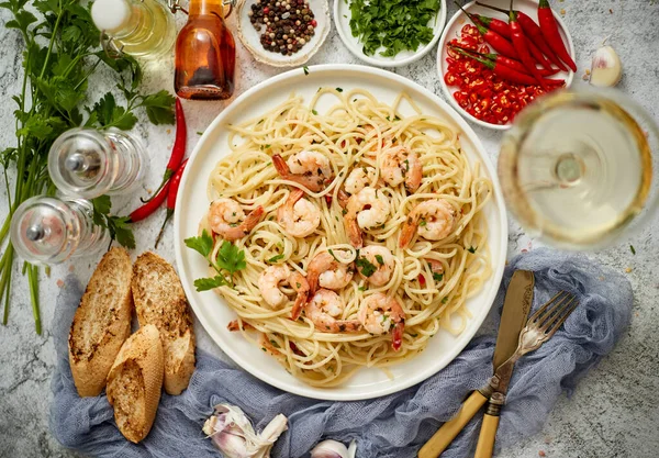 Spaghetti aux crevettes sur plaque de céramique blanche et servi avec un verre de vin blanc — Photo