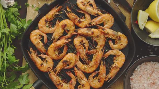 Crevettes tigrées rôties sur une poêle à griller en fer avec persley frais, citron, piment et pain — Video