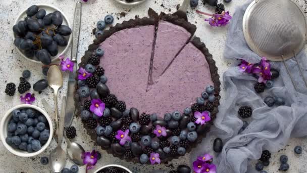 Tarta dulce y sabrosa con arándanos frescos, moras y uvas, servida sobre fondo de piedra — Vídeo de stock