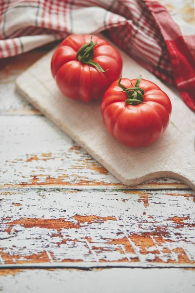 Widok z góry na białą deskę z soczystymi pomidorami na drewnianym stole — Zdjęcie stockowe