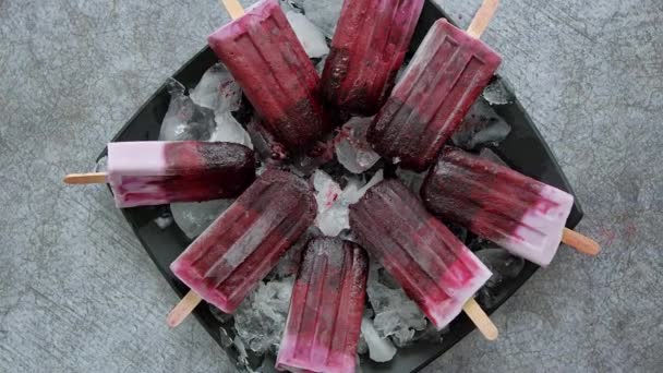 Domowej roboty świeży mrożone jagody i jeżyny popsicles na czarnej płycie z lodem siedzi na kamieniu — Wideo stockowe