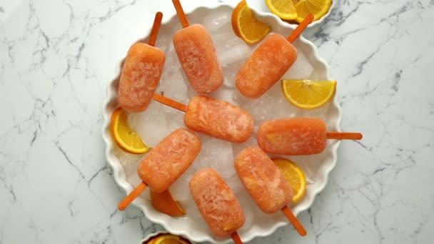 Domowej roboty, soczyste, pomarańczowe lody. Umieszczony na białym talerzu z kostkami lodu — Wideo stockowe