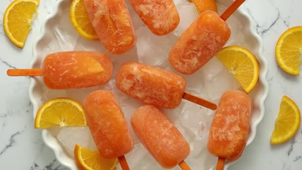 Házi készítésű, lédús, narancsos jégkrém. Fehér tányérra helyezve, jégkockákkal — Stock videók