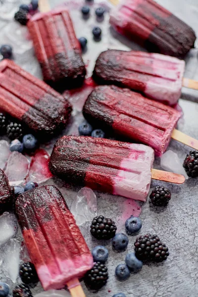 Homemade blackberry and cream ice-creams or popsicles with frozen berries on black slate tray — Stock Photo, Image