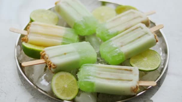 Summer refreshing homemade lime popsicles with chipped ice over stone background — Stock Video