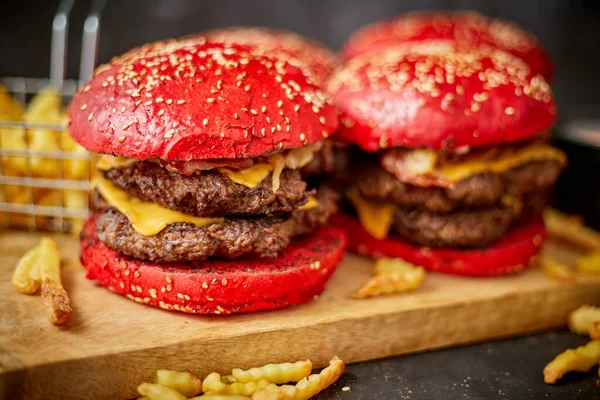 Set dari empat raksasa buatan sendiri Becon burger keju ganda. Disajikan dengan kentang goreng di papan kayu. — Stok Foto