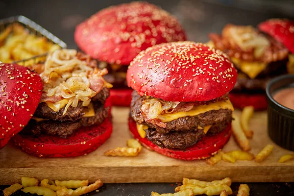 Een set van rode broodjes zelfgemaakte heerlijke hamburgers van rundvlees, spek, kaas, gegrilde ui op een donkere roestige — Stockfoto
