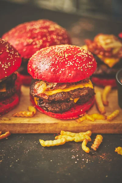 Egy sor piros zsemle házi készítésű finom hamburger marhahúsból, szalonnából, sajtból, grillezett hagymából egy sötét rozsdás — Stock Fotó