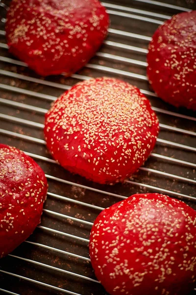 Pães de hambúrguer caseiros vermelhos cozidos no forno com vista superior de sésamo. Colocado em grade de metal . — Fotografia de Stock