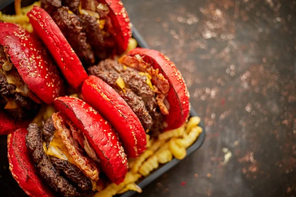 Set van vier zelfgemaakte dubbele becon kaas hamburgers. Geserveerd met frites op houten plank. — Stockfoto