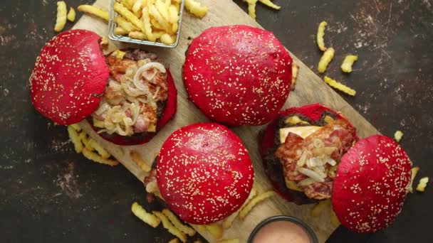 Een set van rode broodjes zelfgemaakte heerlijke hamburgers van rundvlees, spek, kaas, gegrilde ui op een donkere roestige — Stockvideo