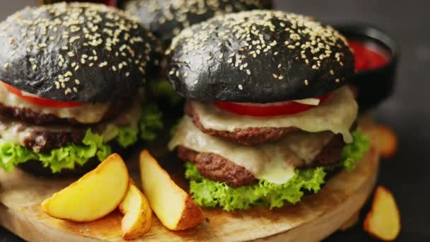 Černý dvojitý hamburgery se sýrem. Cheeseburgery z Japonska s černou houskou na tmavém pozadí — Stock video