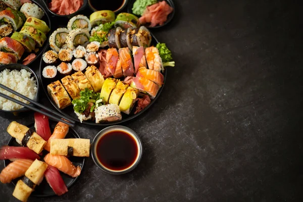Surtido de sushi servido sobre fondo oscuro oscuro. Vista superior de mariscos, varios rollos maki — Foto de Stock