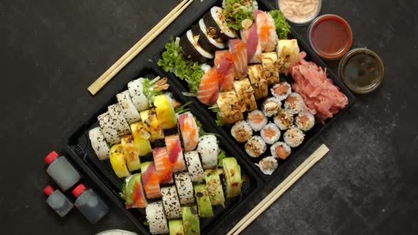 Comida asiática a domicilio, varios sets de sushi en envases de plástico con salsas, arroz y palillos — Vídeos de Stock